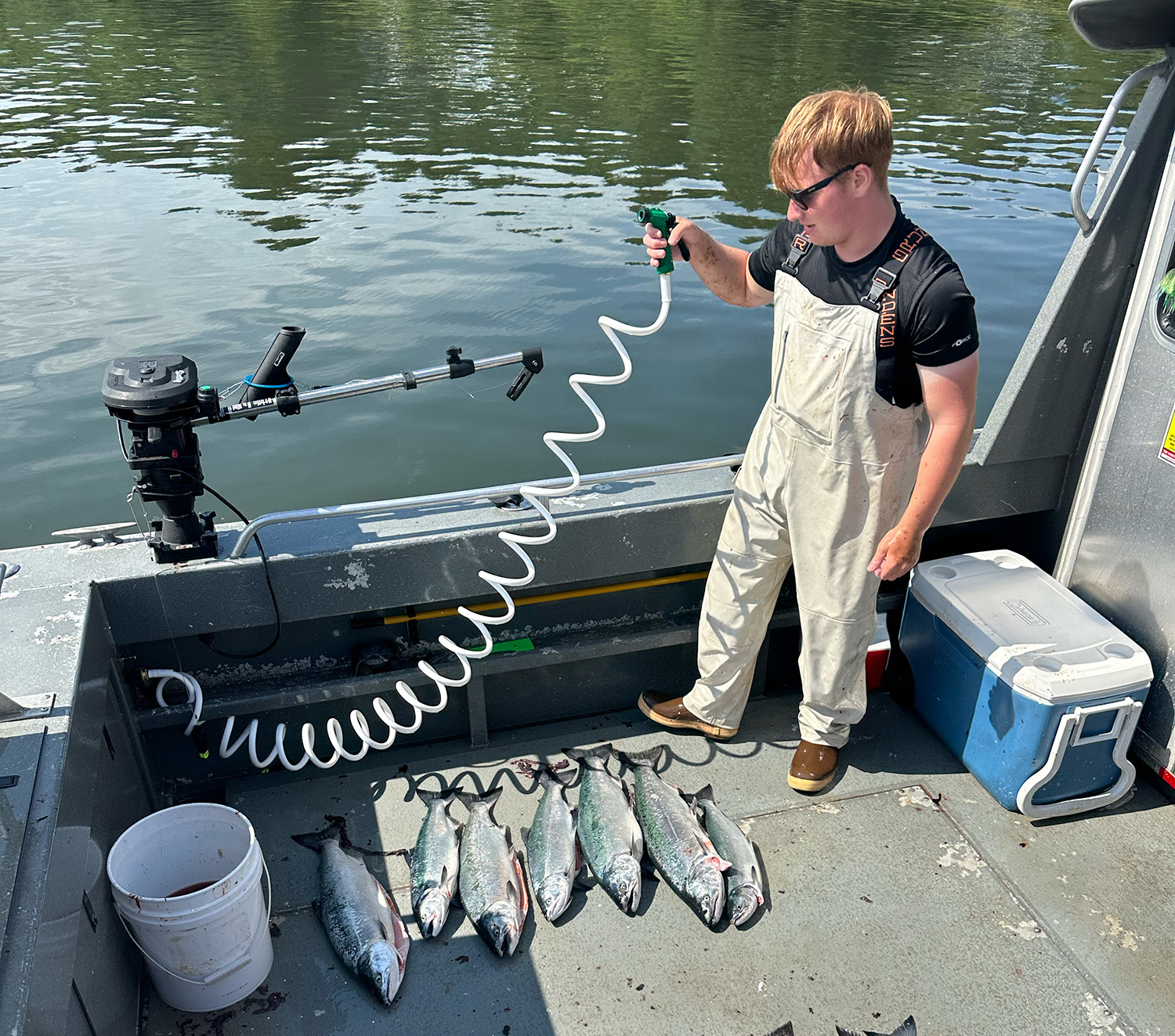 A crew member washes the deck near a fresh catch, showing what it's like to work in alaska fishing.
