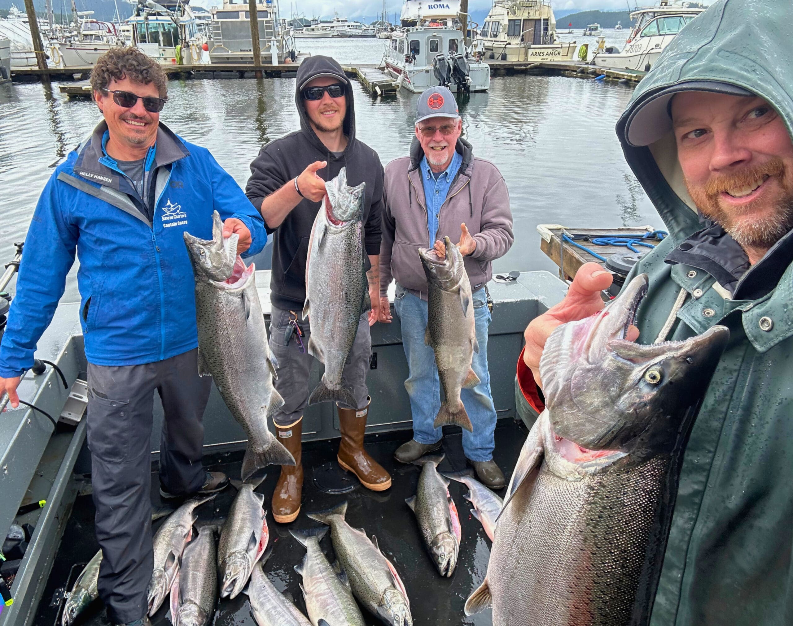 A group showing off their salmon catch at the dock during the best time to salmon fish in alaska.
