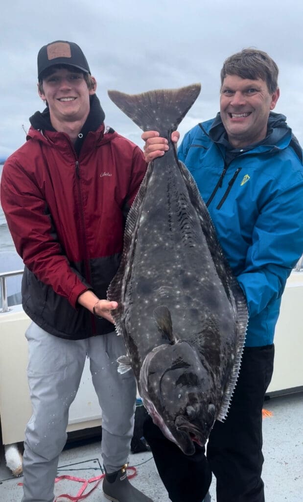 Two anglers holding a large Pacific halibut on a Juneau charter during the best time to fish in Alaska for halibut